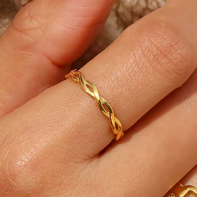 Gold ring with a twisted design on a finger