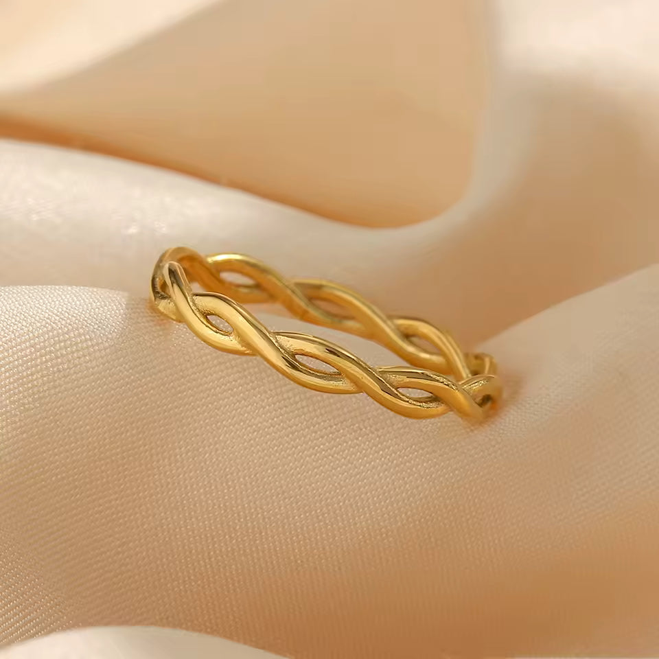 Gold braided ring on a mannequin hand against a beige background