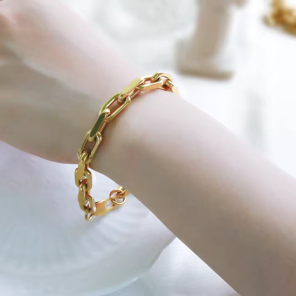 Gold chain bracelet on a wrist with a blurred background