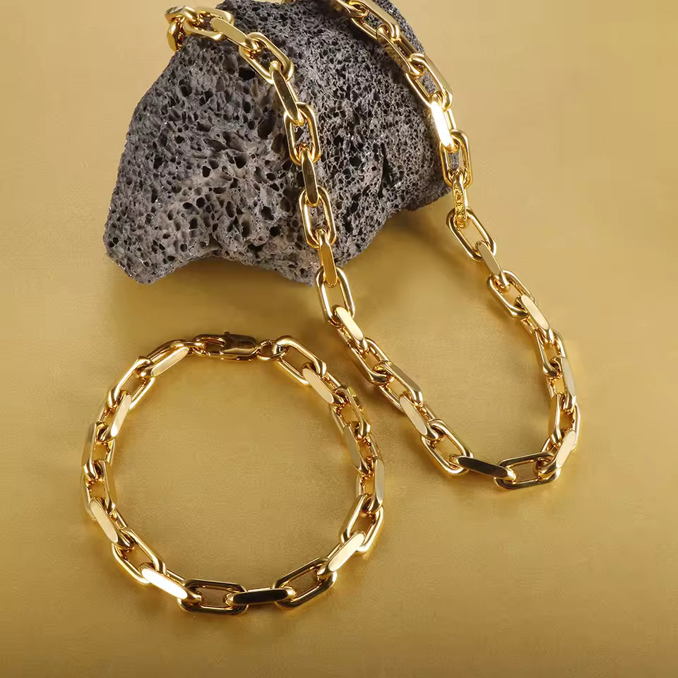 Gold chain bracelet and necklace on a textured stone surface with a gold background