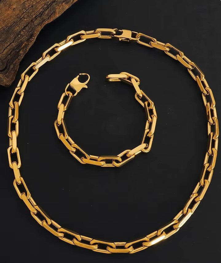 Gold chain necklace and bracelet on a dark surface