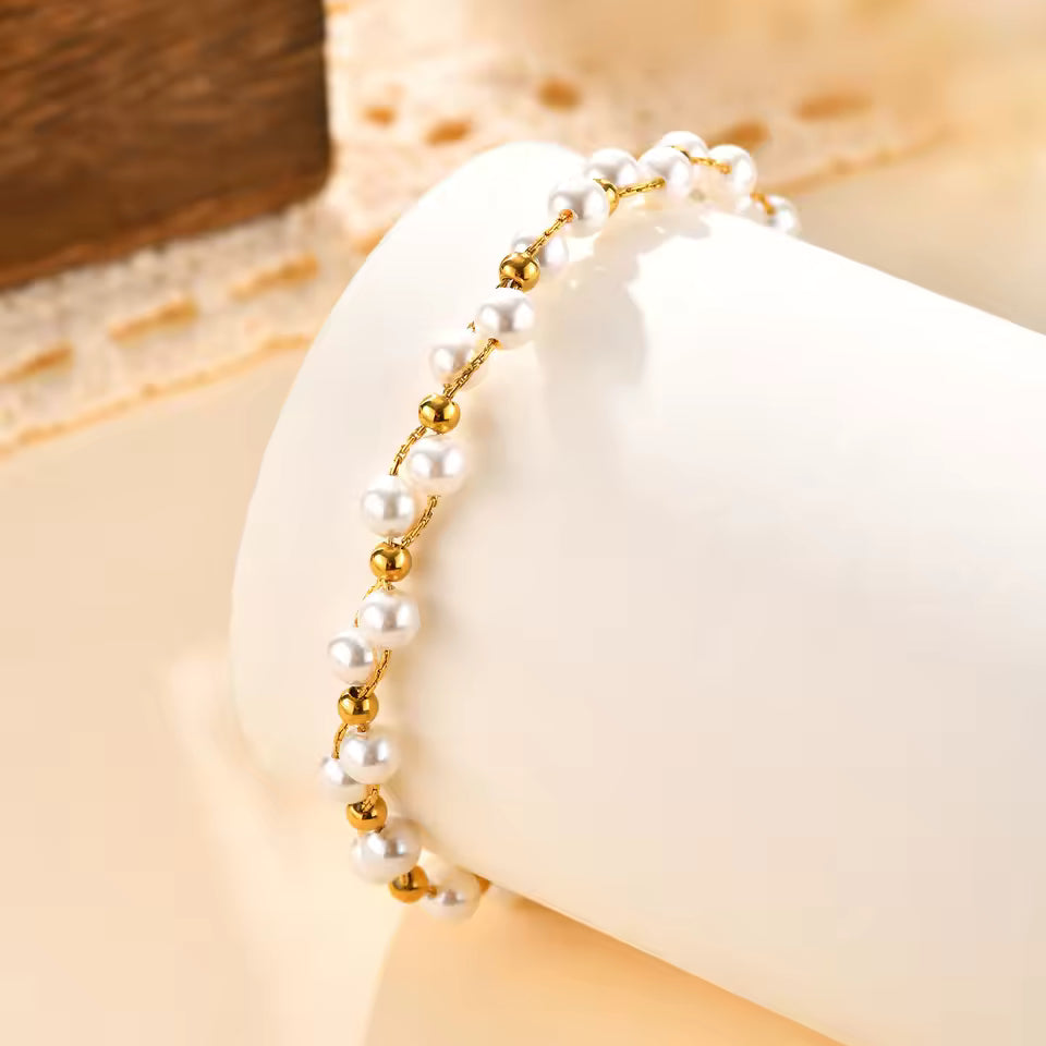 Pearl bracelet with gold beads on a white cushion