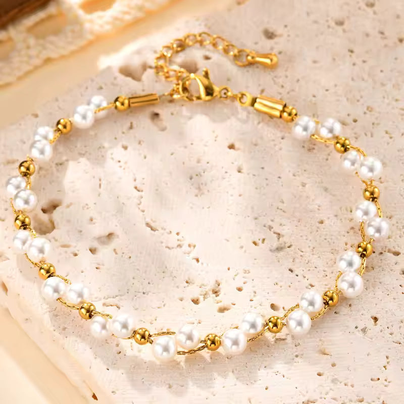 Pearl bracelet with gold accents on a textured beige surface
