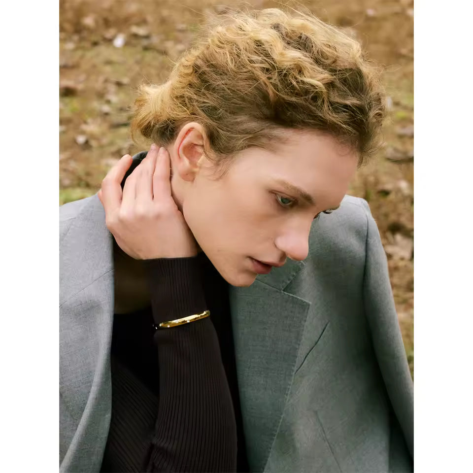 Person wearing a gray coat with a blurred natural background