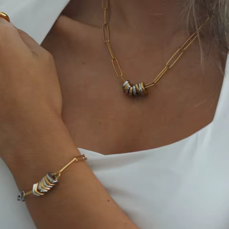 Gold necklace and bracelet on a person wearing a white top
