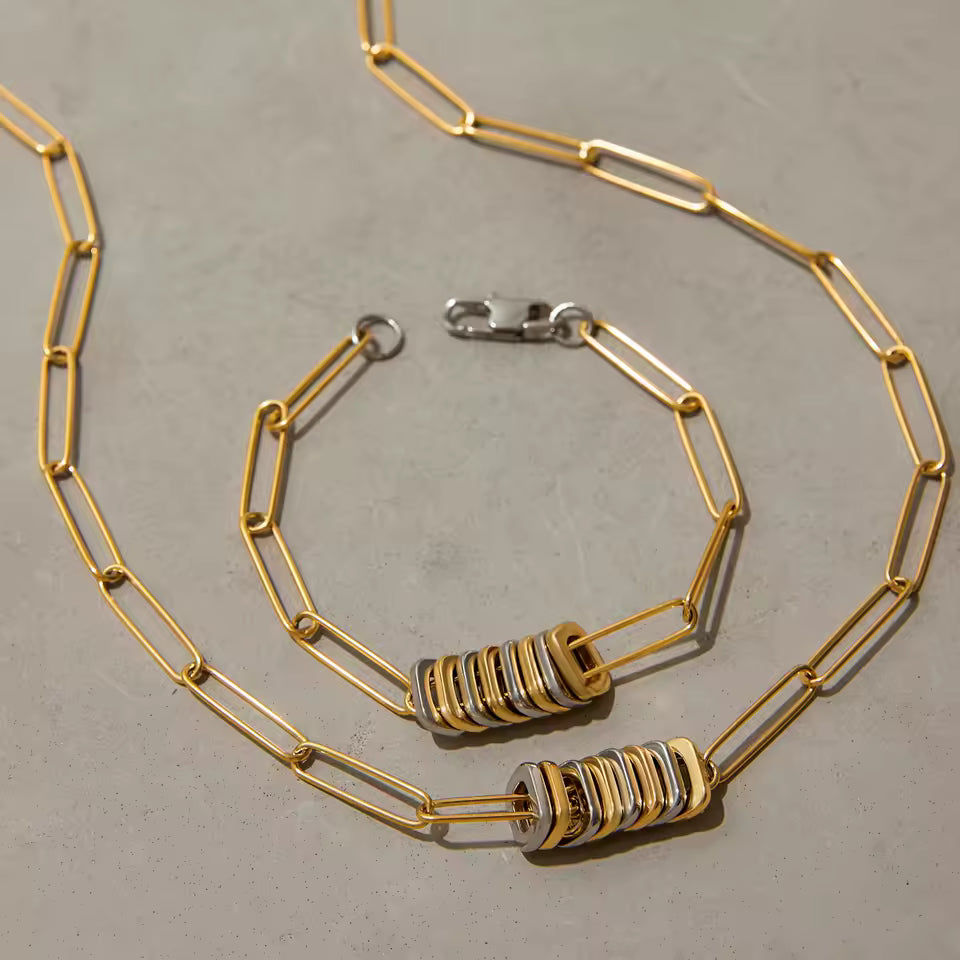 Gold chain necklace with decorative pendents on a gray surface