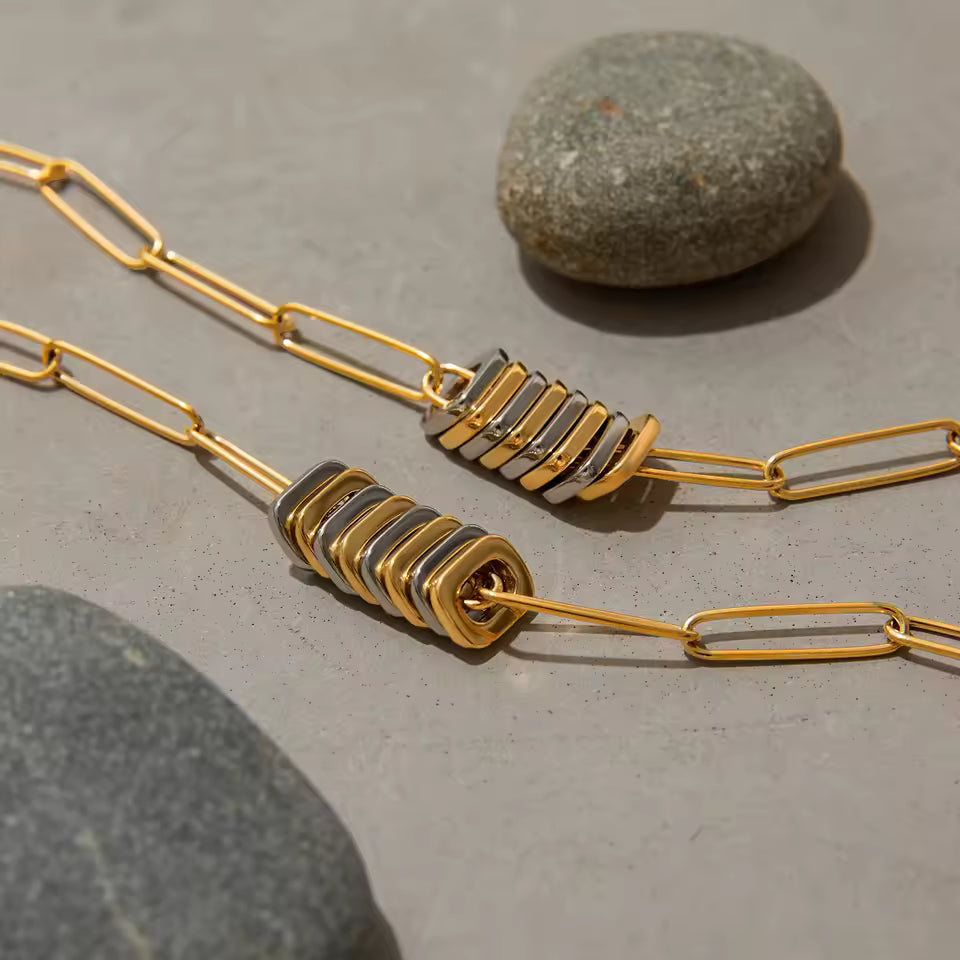 Gold and silver necklace on a concrete surface with stones