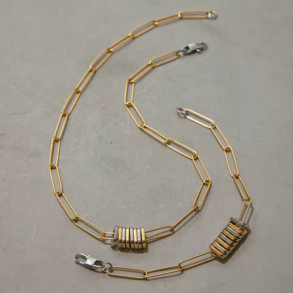 Gold chain necklace with metal clasp on a gray surface