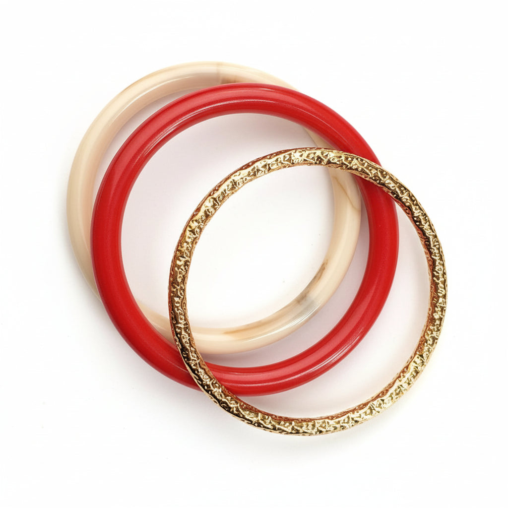 Three bracelets, including a gold one, on a white fabric background