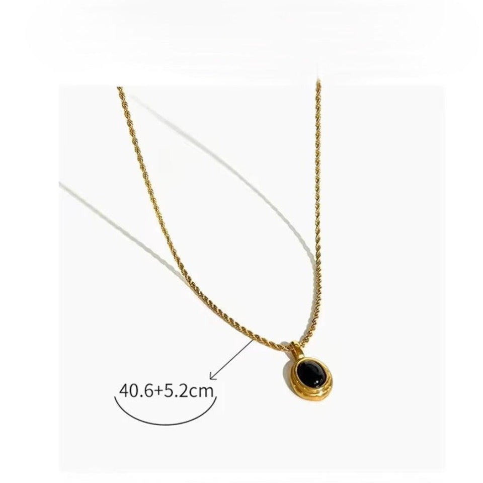 Gold necklace with a black pendant on a white background