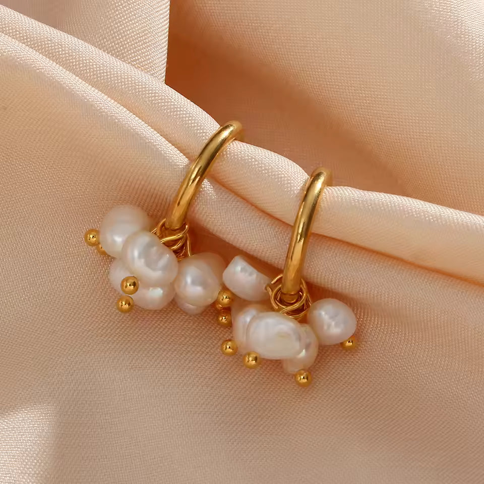 Gold hoop earrings with pearls on a beige fabric background