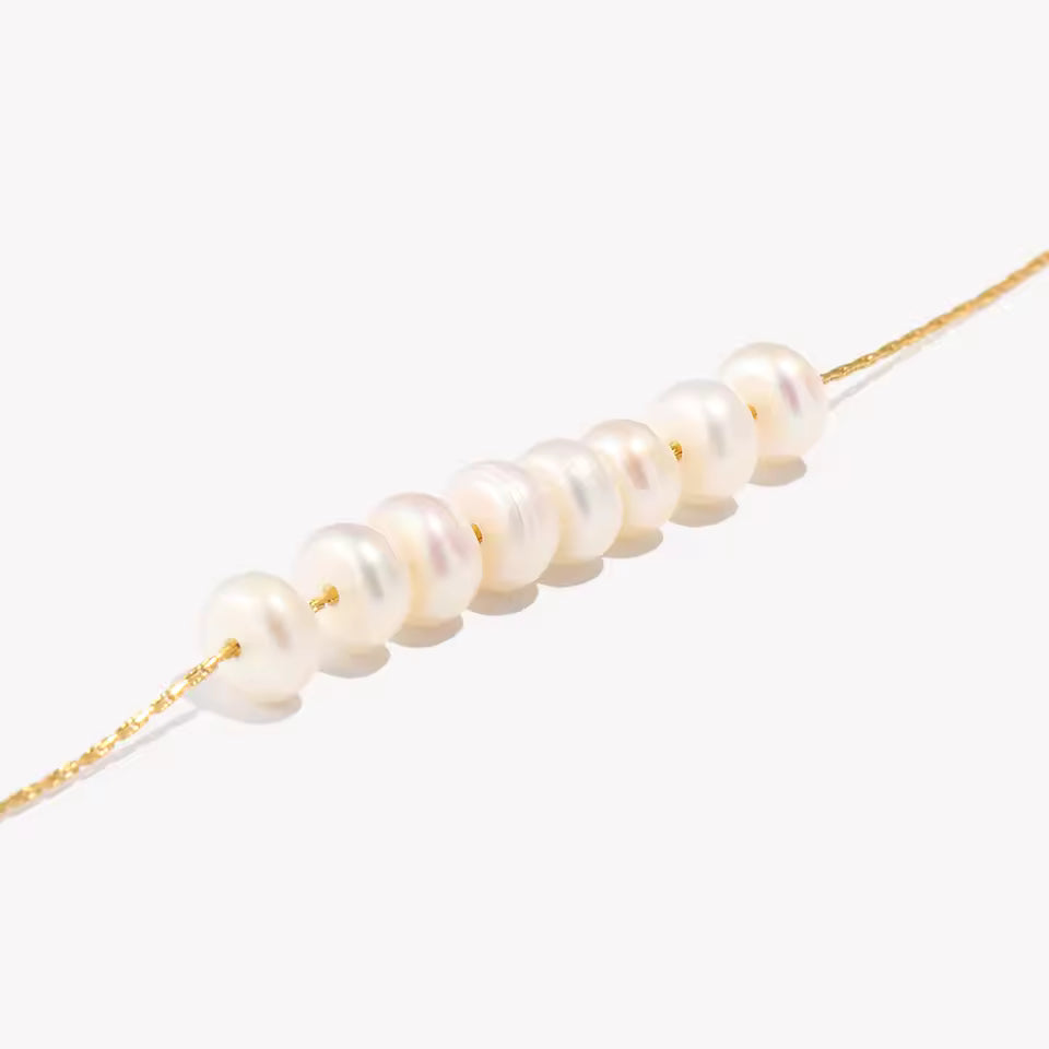 Gold necklace with white pearls on a white background