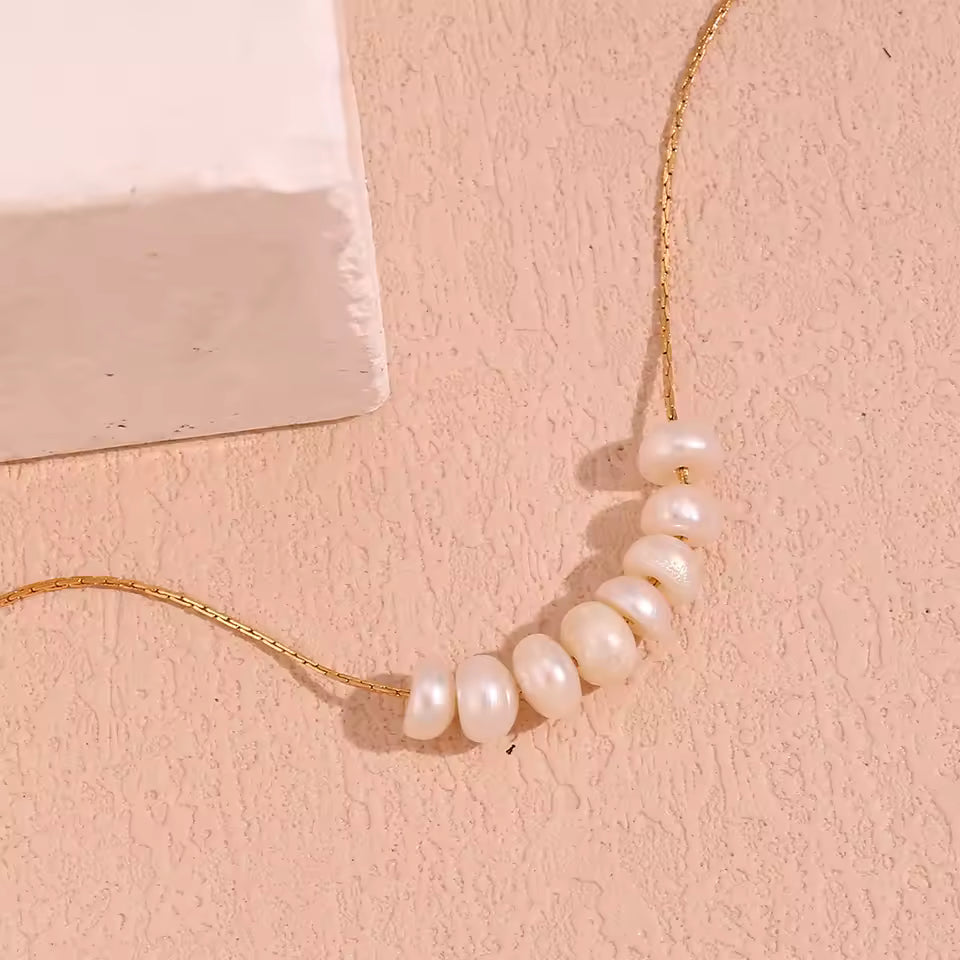 Pearl necklace on a pink textured surface
