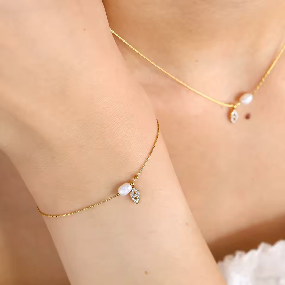 Gold Necklace and Bracelet with pearl accents on a person against a neutral background