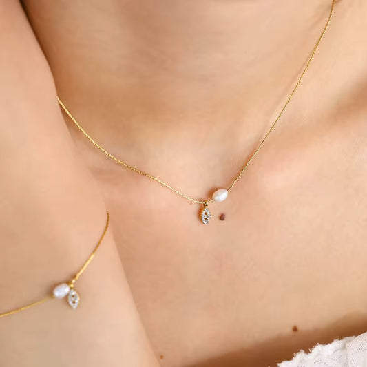 Gold necklaces with pearl pendants on a person's neck