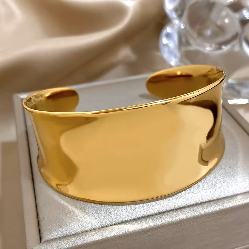 Gold bracelet on a reflective surface with a soft beige background