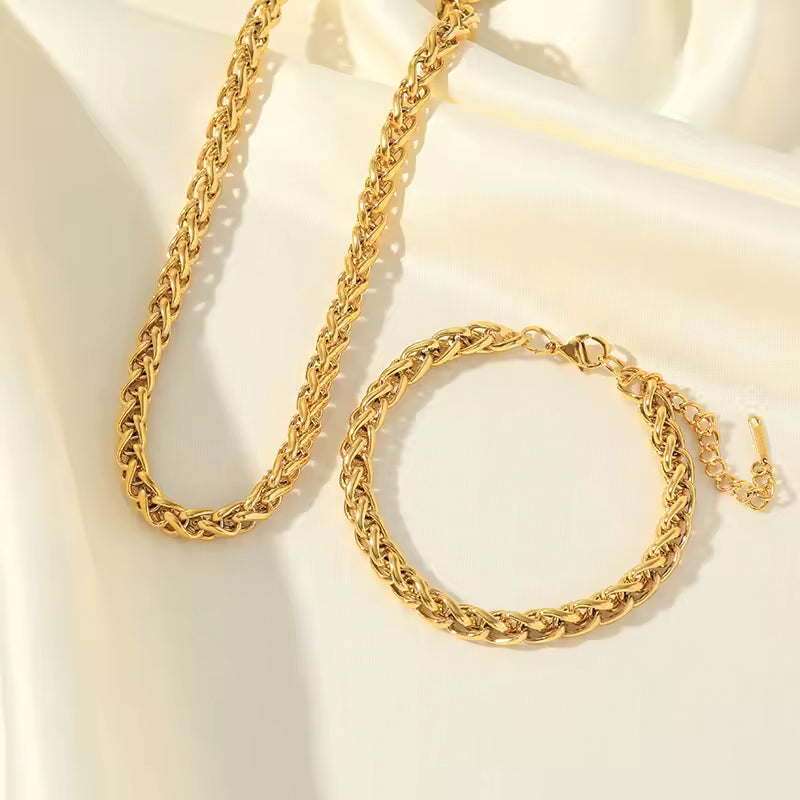 Gold chain necklace and bracelet on a light beige background