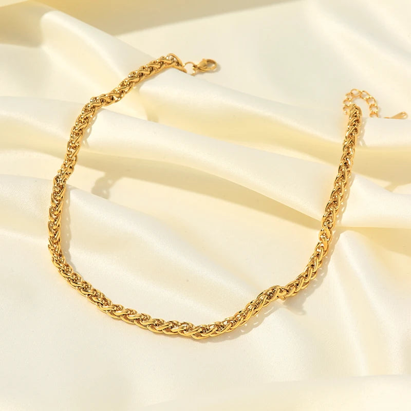 Gold chain necklace on a soft beige fabric background