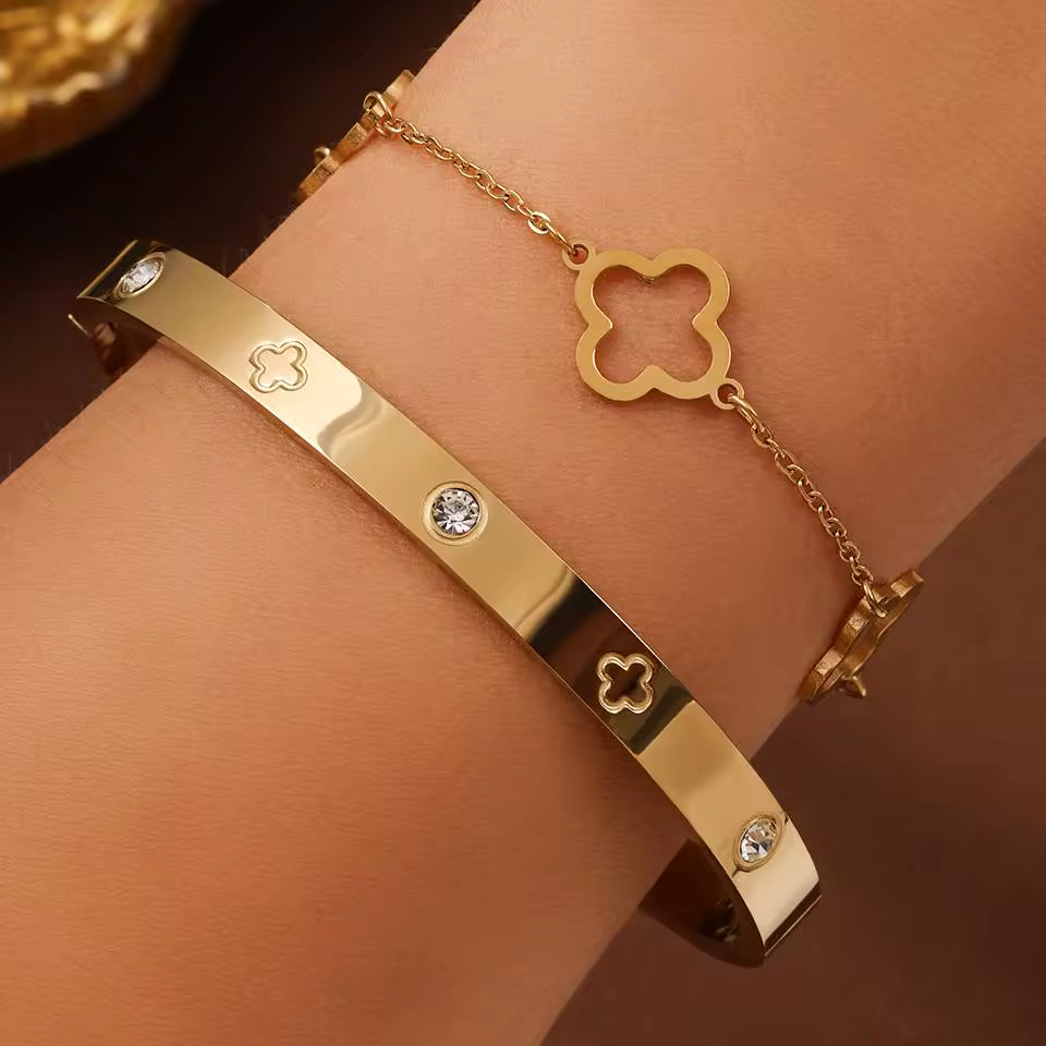 Gold bracelet with clover designs on a wrist against a brown background