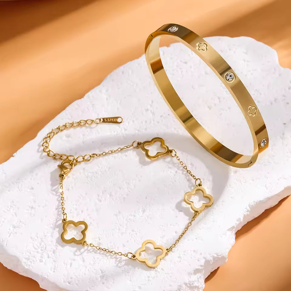 Gold bracelet with clover designs on a textured white surface