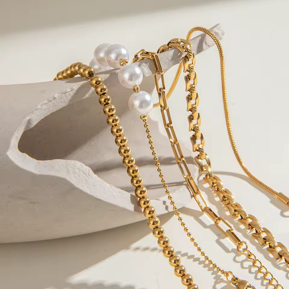 Three gold bracelets with pearls on a light background