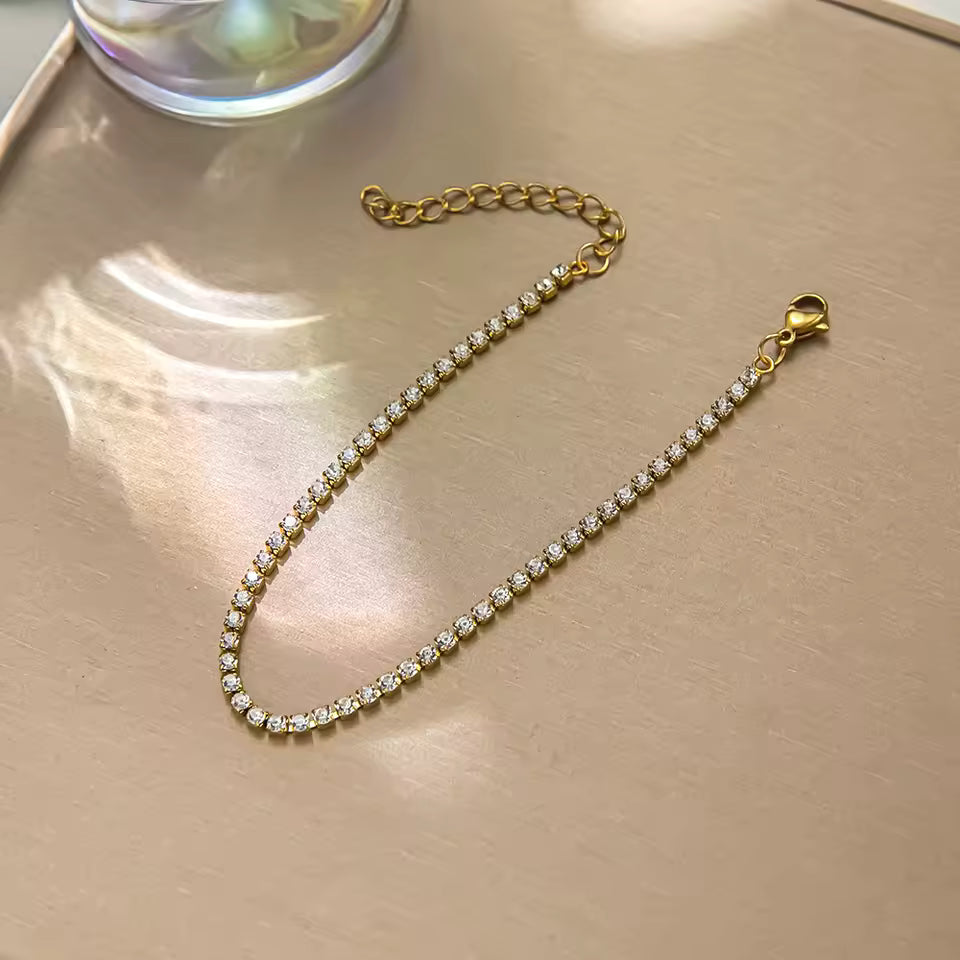 Gold bracelet with clear stones on a beige surface