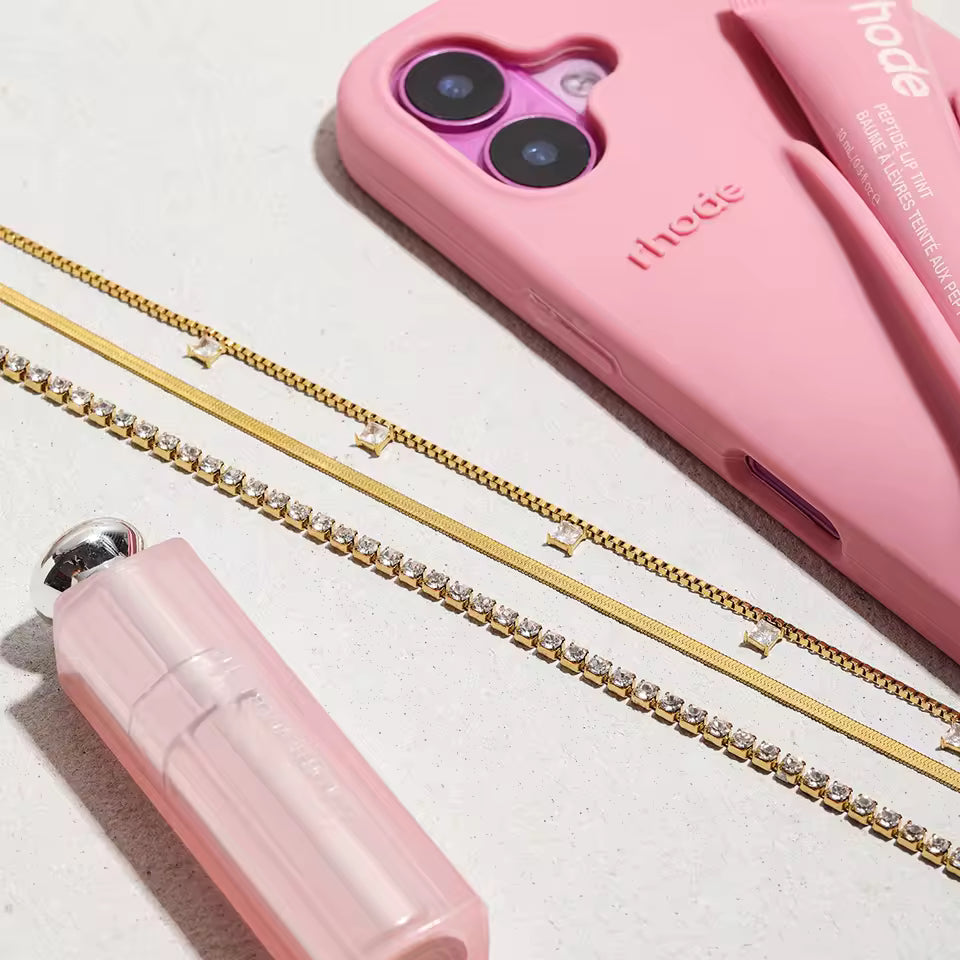Pink phone case and lipstick with gold chain on a light background