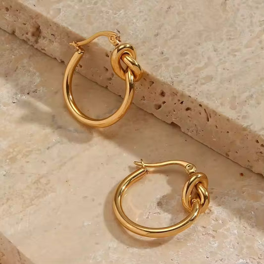 Pair of gold hoop earrings on a textured beige surface
