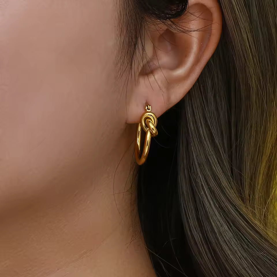 Gold hoop earring worn by a person with dark hair.