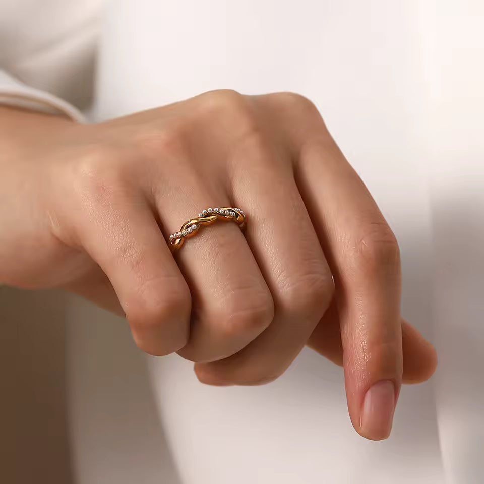 Hand wearing a gold ring on a neutral background