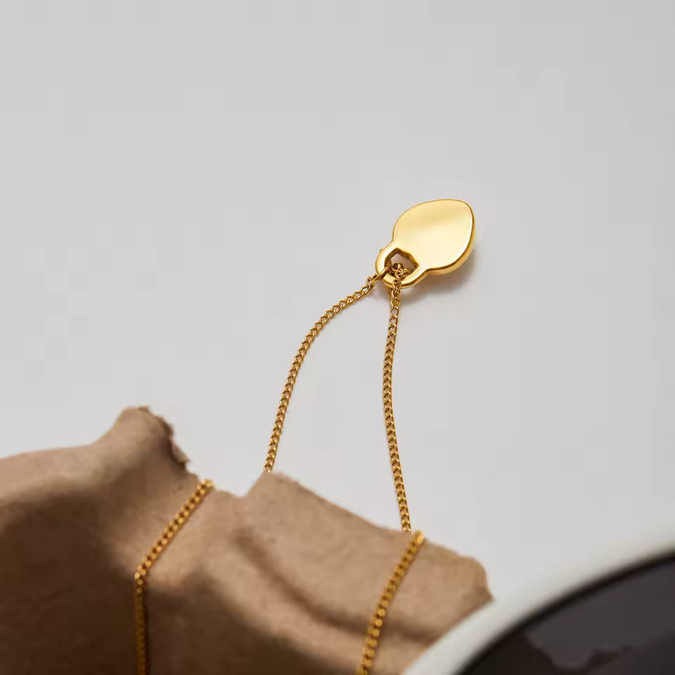 Gold chain heart pendant on a light grey background