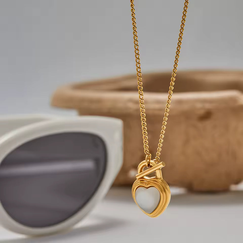 Gold necklace with a heart-shaped pendant on a neutral background