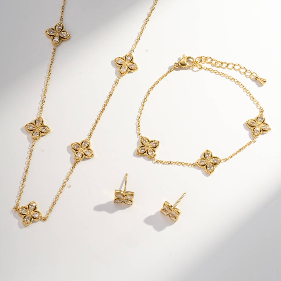 Gold jewelry set with necklace, bracelet, and earrings on a light gray background