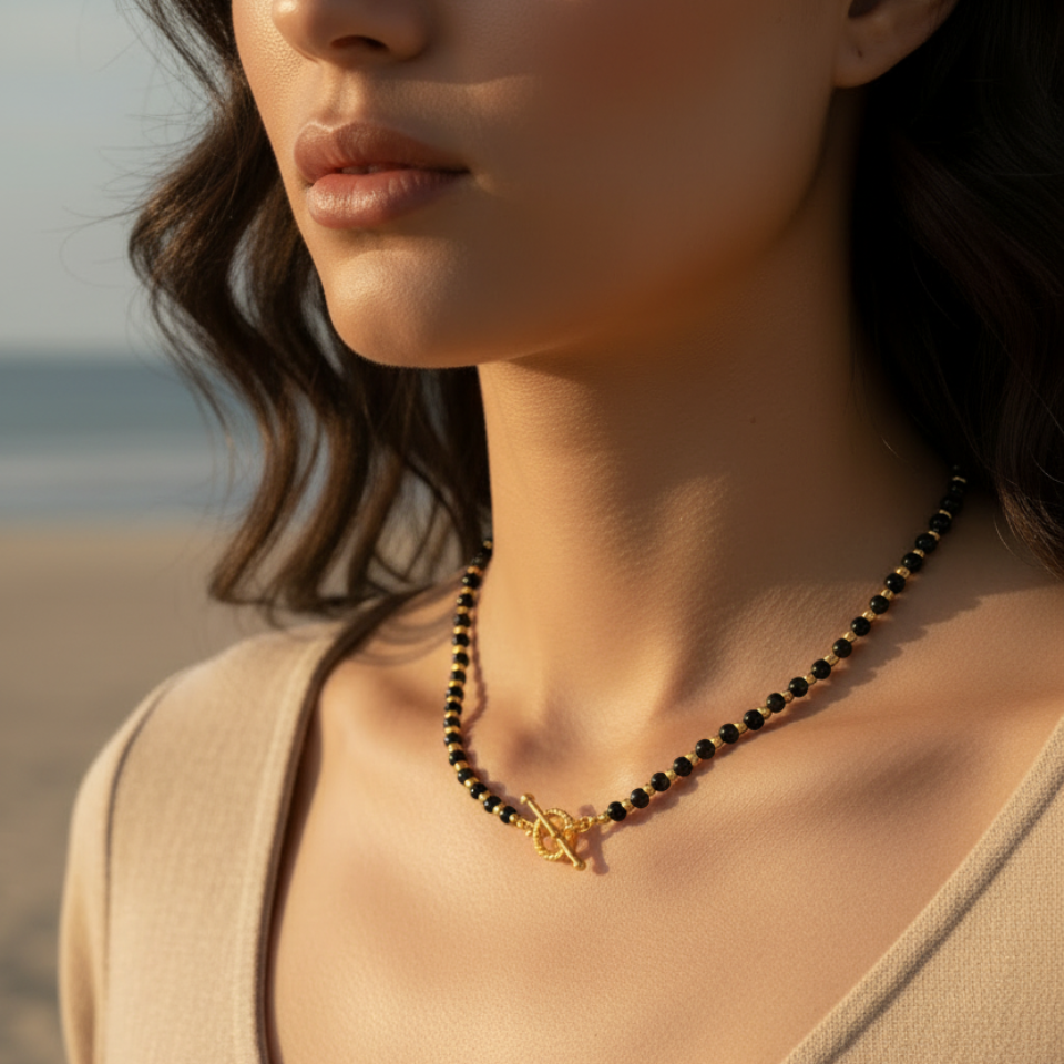 Close-up of a woman wearing a necklace with a blurred beach background