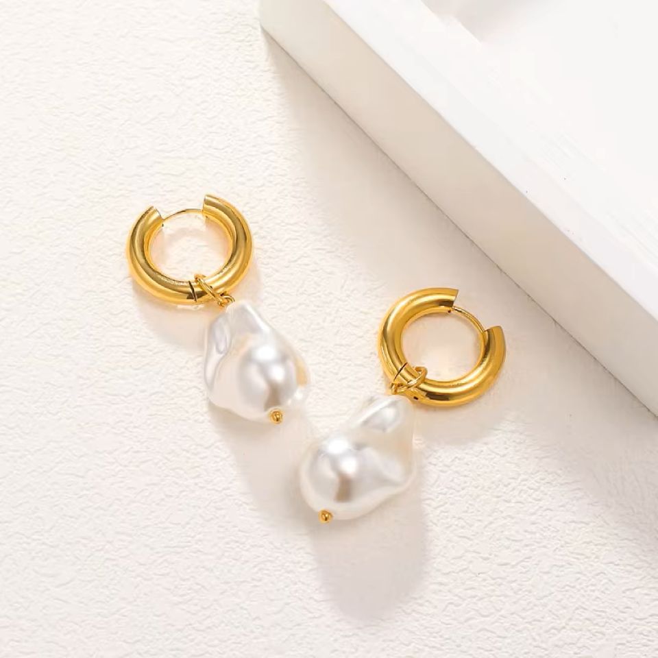 Gold hoop earrings with pearl-like stones on a light background