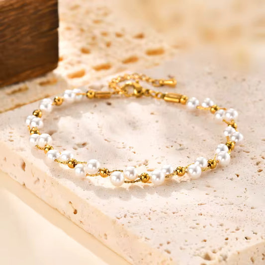 Pearl and gold bracelet on a textured beige surface