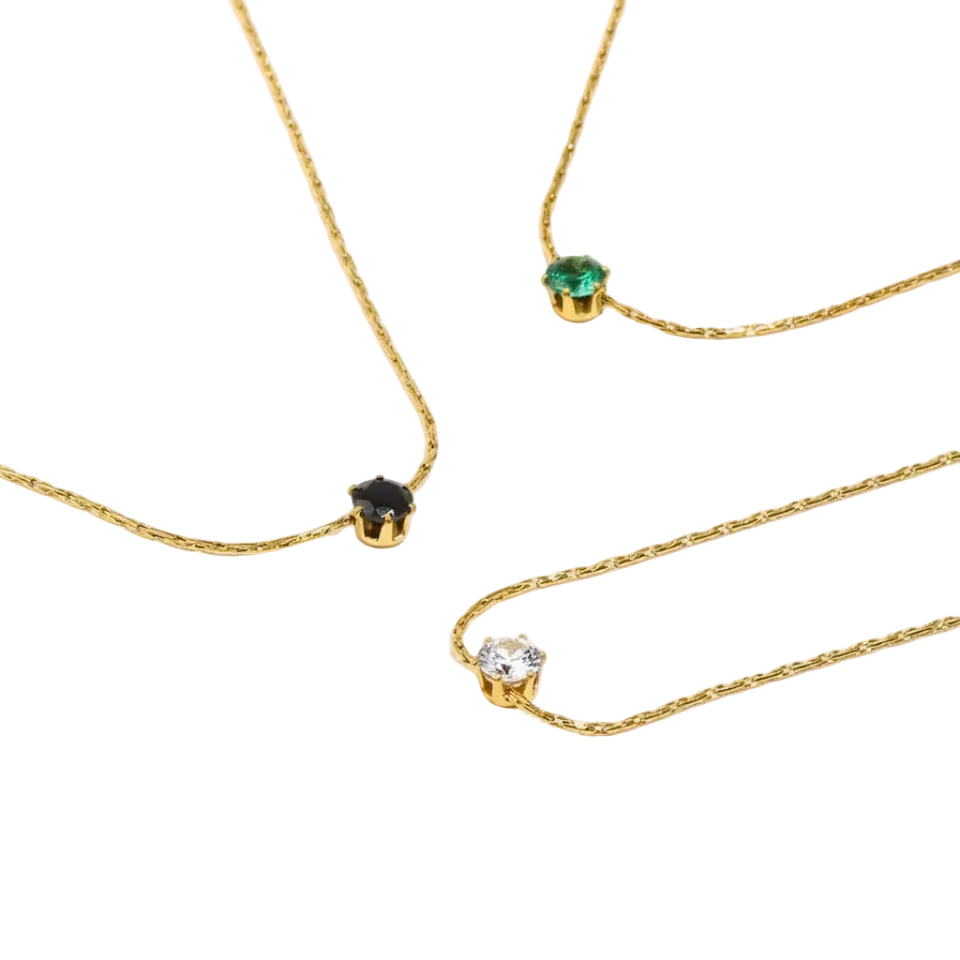 Three gold necklaces with gemstones on a white background