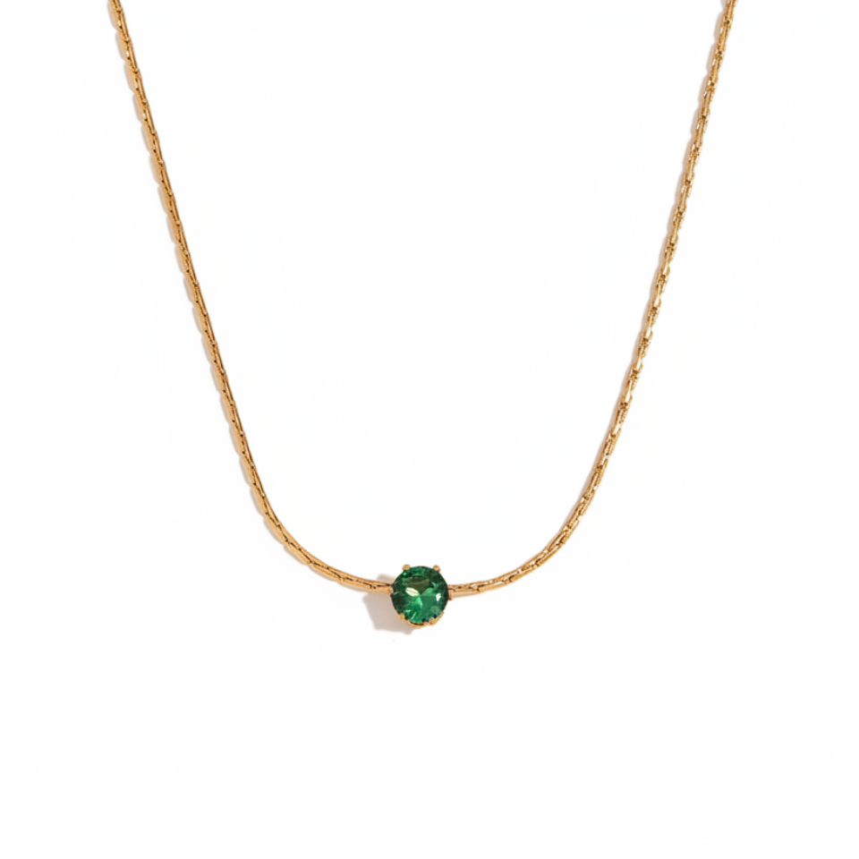 Gold necklace with a green gemstone,  don a white background.