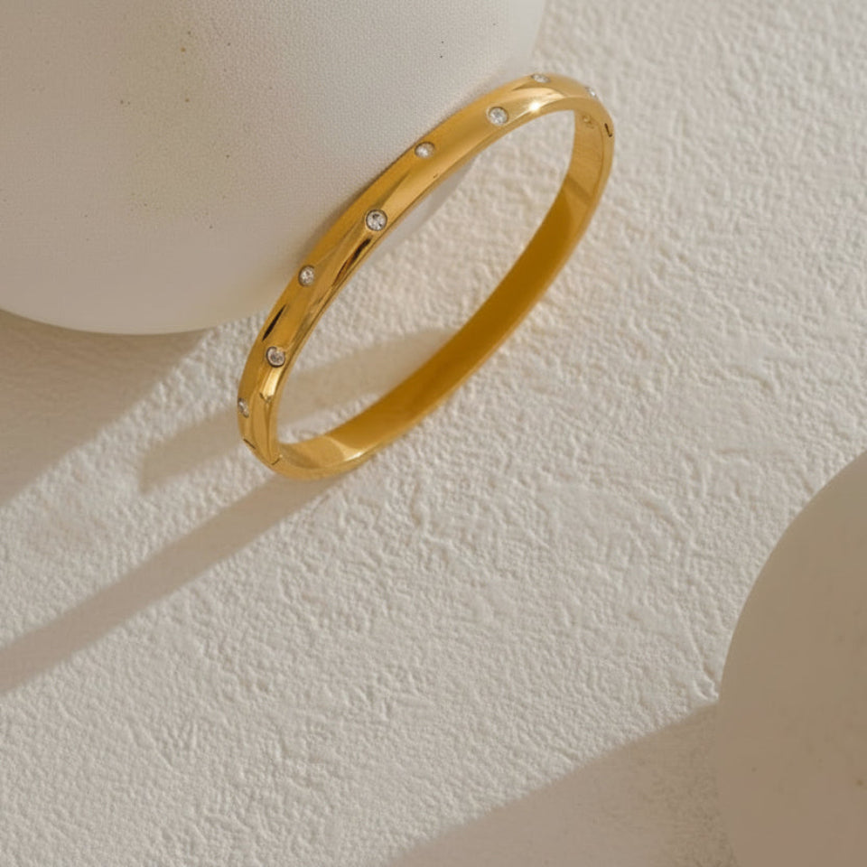 Gold  bangle on a textured beige surface