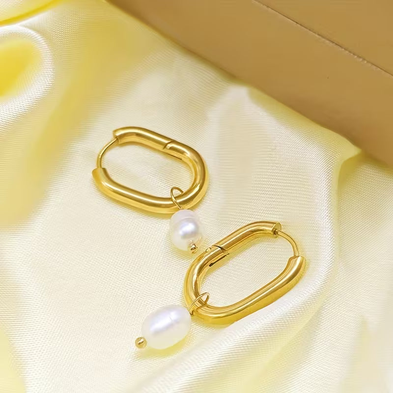Gold hoop earrings with pearls on a yellow satin surface