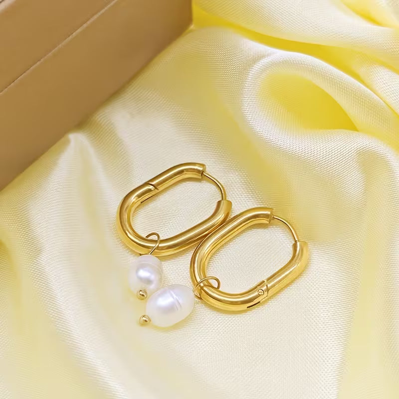 Gold hoop earrings with pearls on a yellow fabric background