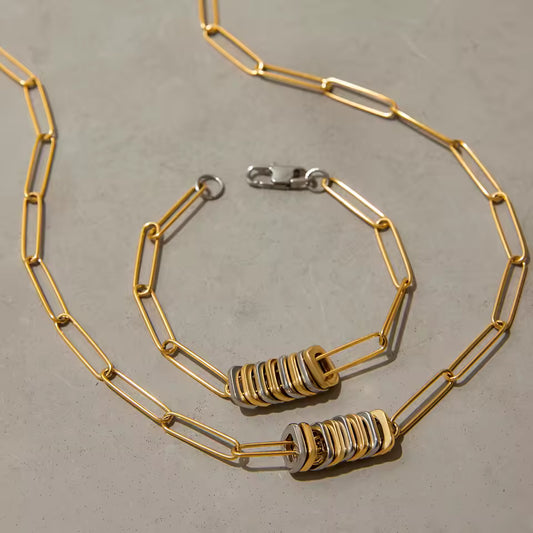Gold chain necklace with decorative pendents on a gray surface