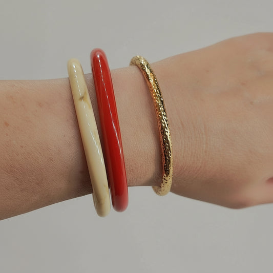 Three bracelets on a wrist against a light background