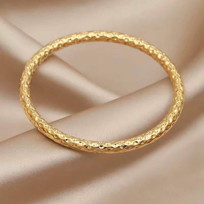 Gold bracelet on a beige fabric background