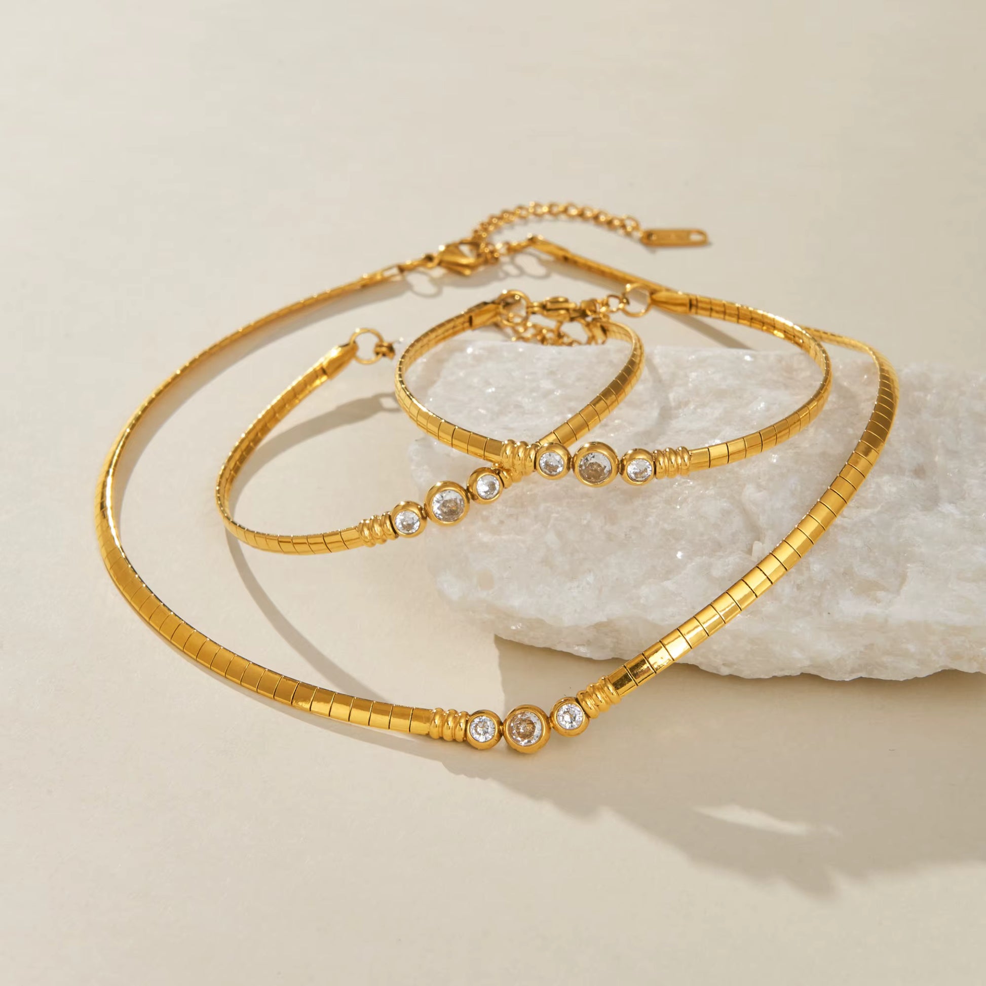 Gold bracelet with embedded crystals on a textured beige surface