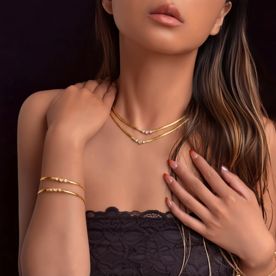 Woman wearing gold necklaces and bracelets against a dark background