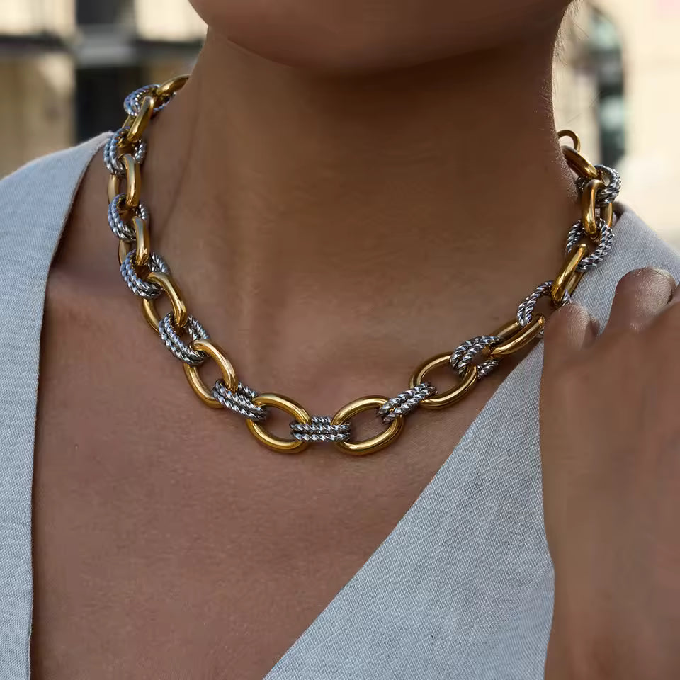 Gold and silver chain necklace worn by a person with a blurred background