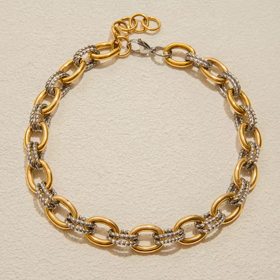 Gold and silver chain necklace on a beige background