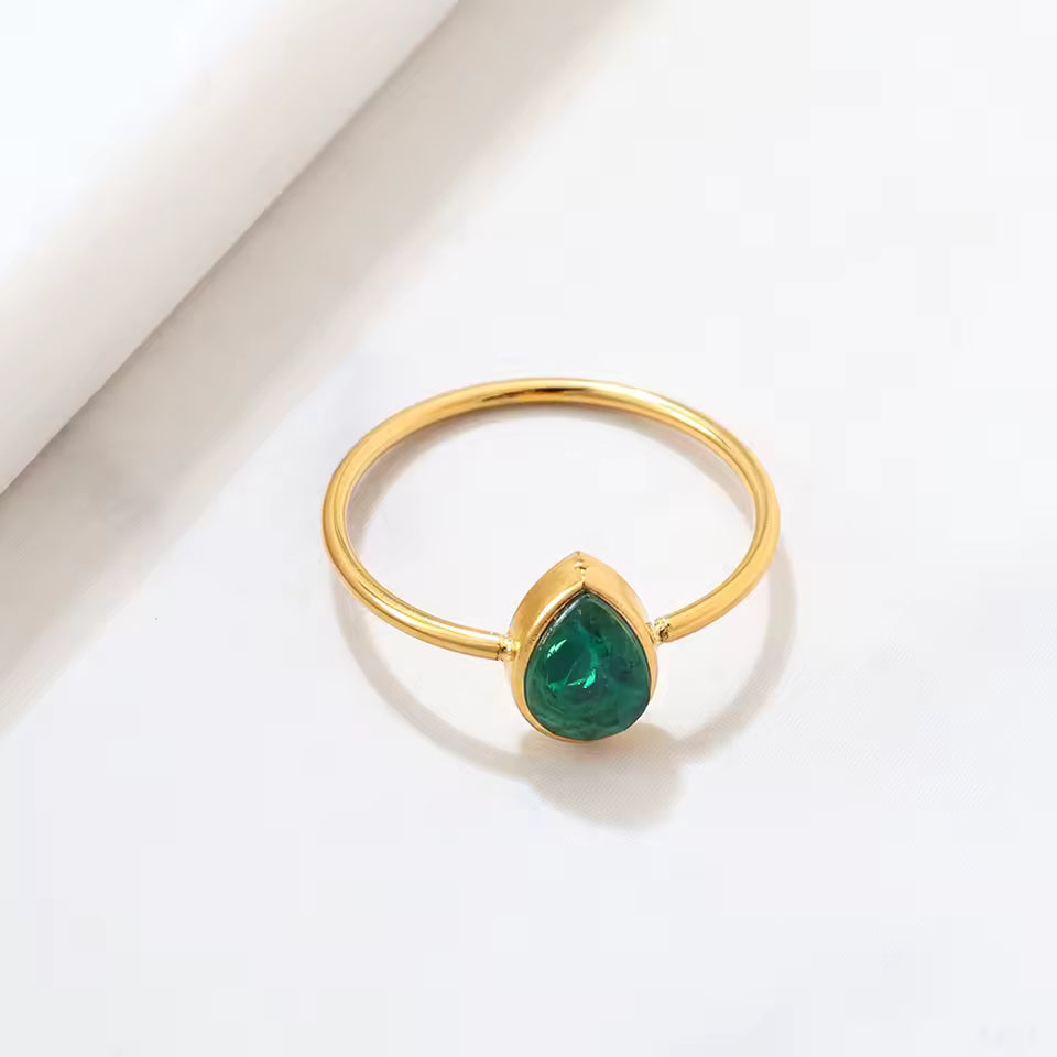 Gold ring with a green gemstone on a light background