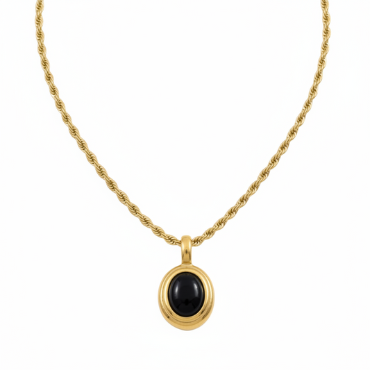 Gold necklace with a black pendant on a white background